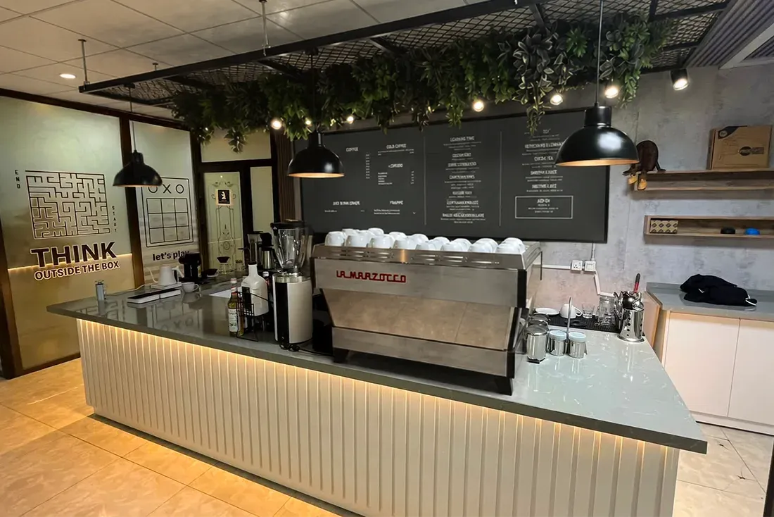 Espresso makinesi, menü panosu ve sarkan bitkileriyle bitmiş Nava Brew barının fotoğrafı